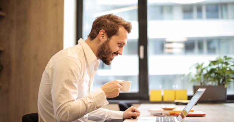 Laptop - Man Holding Teacup Infront of Laptop on Top of Table Inside the Room